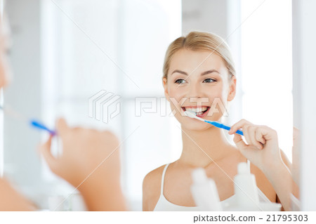 woman with toothbrush cleaning teeth at bathroom woman with toothbrush cleaning teeth at bathroom 21795303