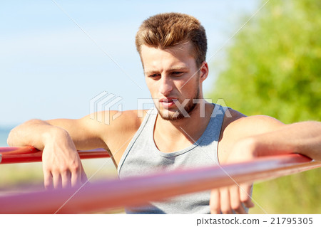 young man exercising on parallel bars outdoors young man exercising on parallel bars outdoors 21795305