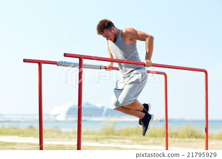young man exercising on parallel bars outdoors young man exercising on parallel bars outdoors 21795929