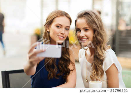 happy women with smartphone taking selfie at cafe happy women with smartphone taking selfie at cafe 21796361