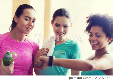 happy women showing time on wrist watch in gym 21797268
