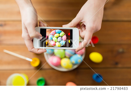close up of hands with easter eggs and smartphone 21798483