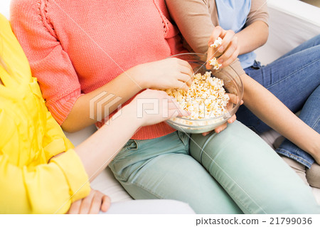 close up of teenage girls eating popcorn at home close up of teenage girls eating popcorn at home 21799036