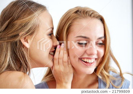happy young women whispering gossip at home happy young women whispering gossip at home 21799809