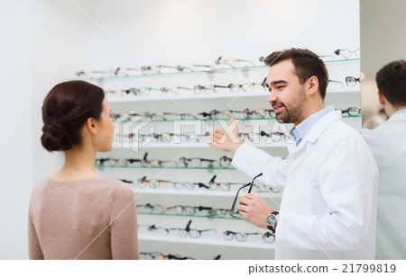 woman and optician showing glasses at optics store 21799819