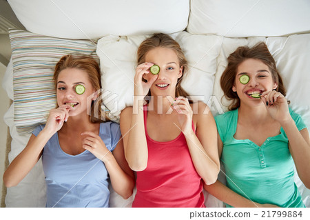 happy young women with cucumber mask lying in bed happy young women with cucumber mask lying in bed 21799884