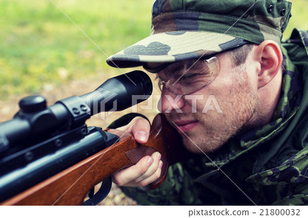 close up of soldier or hunter with gun in forest 21800032