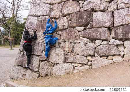 Two ninja climbing stone walls 21809581
