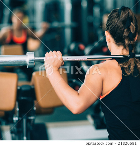 Woman exercising in gym with  barbell 21820681