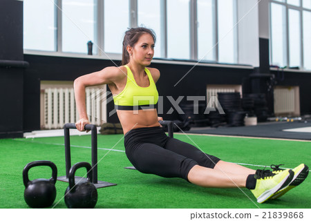 sideview of a sporty woman doing l-sits exercises sideview of a sporty woman doing l-sits exercises 21839868