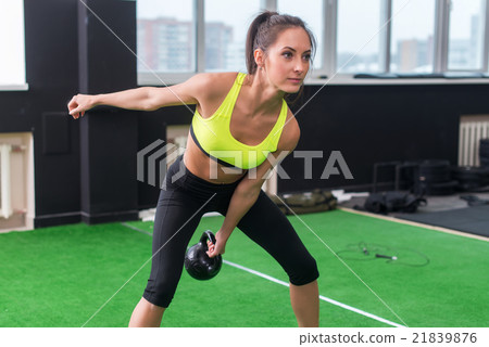 sporty woman doing work-out swinging kettlebell in sporty woman doing work-out swinging kettlebell in 21839876