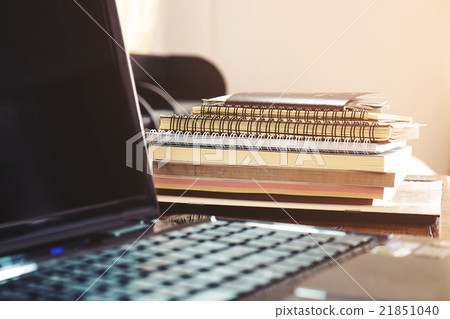 Pile of books and paperwork with blurred laptop Pile of books and paperwork with blurred laptop 21851040