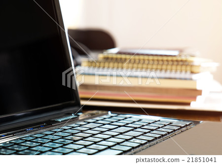 Pile of books and paperwork with blurred laptop Pile of books and paperwork with blurred laptop 21851041