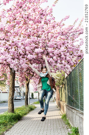 Young caucasian woman is jumping under the flowering sakura tree 21852769