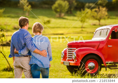 Senior couple hugging, vintage styled red car Senior couple hugging, vintage styled red car 21853844