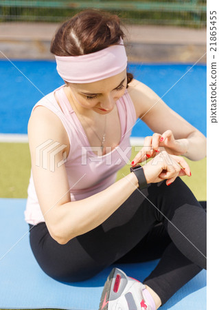 Young sporty woman using fitness wristband watch Young sporty woman using fitness wristband watch 21865455
