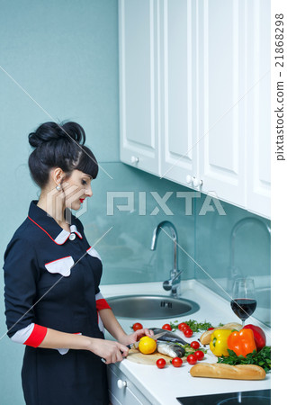 Girl cuts ingredients for dinner in kitchen. Girl cuts ingredients for dinner in kitchen. 21868298