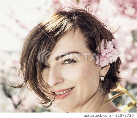 Young caucasian brunette posing with sakura flowers in sunlight 21872726