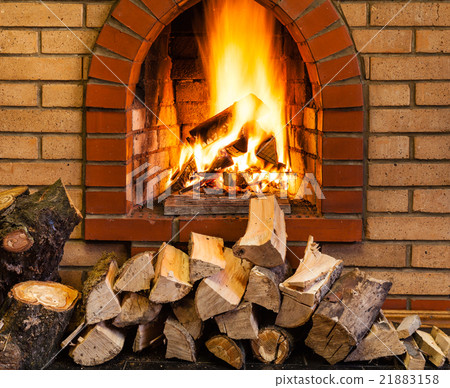 pile of firewood and fire in brick fireplace 21883158