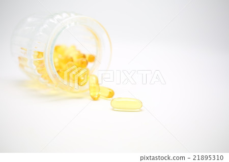 A golden supplement spilled out of the bottle 21895310