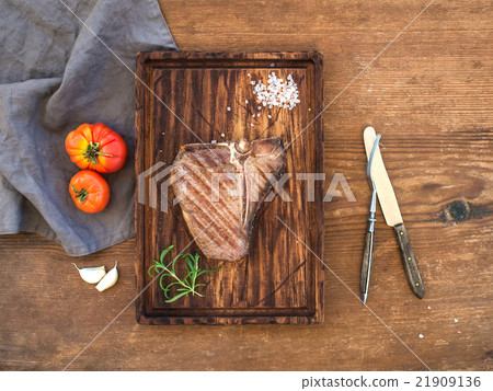 Cooked meat t-bone steak on serving board with 21909136