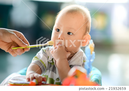 mother feeding baby baby food with a spoon 21932659