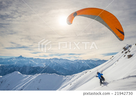 Paraglider launching from snowy slope 21942730
