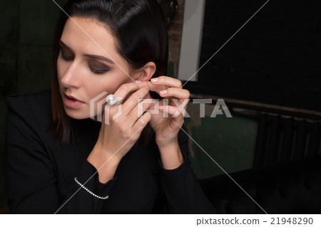 Woman wearing, tries on earring Woman wearing, tries on earring 21948290