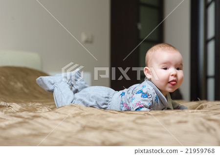 Baby girl lying on belly and grimacing 21959768
