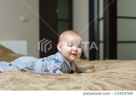 Baby girl lying on belly and grimacing Baby girl lying on belly and grimacing 21959769