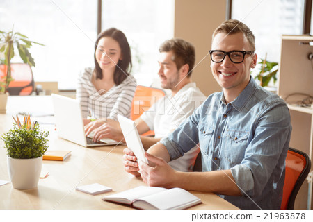 Positive guy sitting at the table in office  21963878