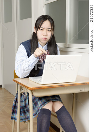 女孩高中生在教室裡用憤怒的面孔操作個人電腦 21972522