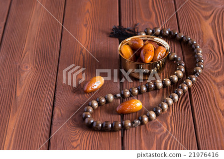 Dates fruit and rosary still life, on a brown Dates fruit and rosary still life, on a brown 21976416
