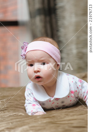 Baby girl lying on belly and grimacing 21976713