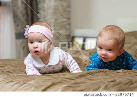 Two babies lying on belly and grimacing 21976714