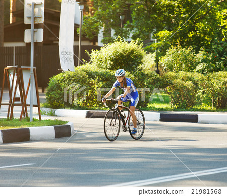 Female cyclist rides a racing bike on road Female cyclist rides a racing bike on road 21981568