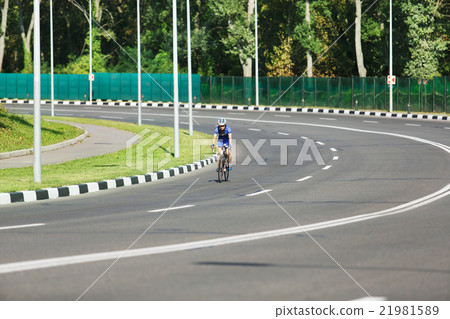 Female cyclist rides a racing bike on road Female cyclist rides a racing bike on road 21981589