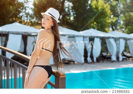 Beautiful young woman standing at a pool Beautiful young woman standing at a pool 21986882