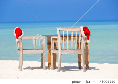 Red santa hats on beach chair at tropical vacation 21995539