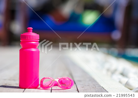 Pink sporty water bottle near swimming pool Pink sporty water bottle near swimming pool 21995543
