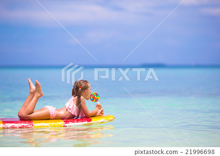 Little girl with lollipop have fun on surfboard in Little girl with lollipop have fun on surfboard in 21996698
