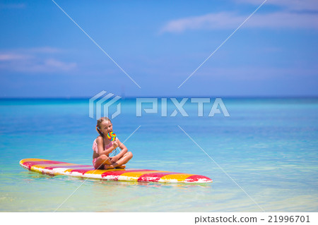 Little girl with lollipop have fun on surfboard in Little girl with lollipop have fun on surfboard in 21996701