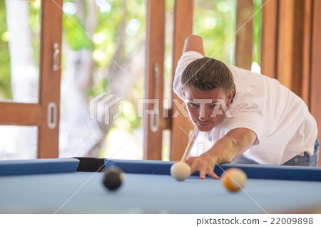 Young man playing billiards on summer vacation Young man playing billiards on summer vacation 22009898