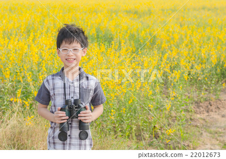 Young Asian boy holding binoculars in flower field Young Asian boy holding binoculars in flower field 22012673