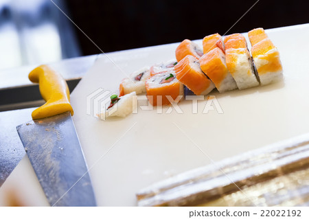 Sushi rolls with salmon lay on cutting board Sushi rolls with salmon lay on cutting board 22022192