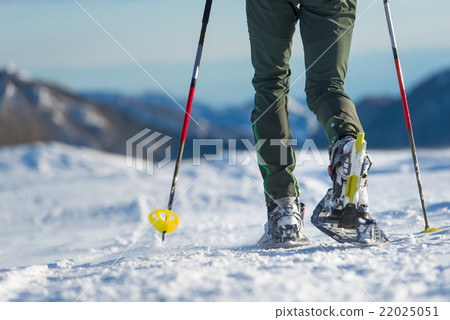 Snowshoes. Snowshoeing closeup. Walking with snowshoes in the sn Snowshoes. Snowshoeing closeup. Walking with snowshoes in the sn 22025051