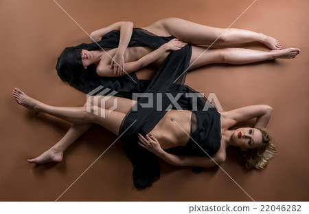 Top view of two nude women posing with fabric 22046282