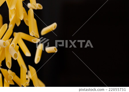 Falling penne pasta. Flying yellow raw macaroni Falling penne pasta. Flying yellow raw macaroni 22055731