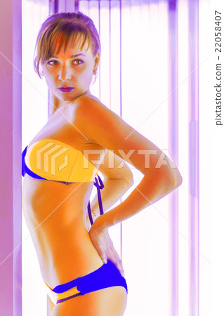 Slim young woman standing in solarium getting sun tan Slim young woman standing in solarium getting sun tan 22058407