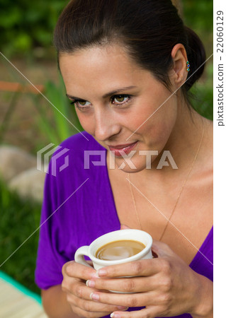 Beautiful young woman drinking coffee outdoors 22060129